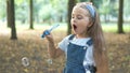 Happy little child girl blowing soap bubbles outside in green park. Outdoor summer activities for children concept Royalty Free Stock Photo