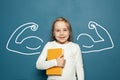 Happy little child girl with book and muscle on blue background. Power in education