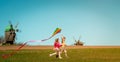 Happy little child girl and boy in front of windmills playing kite. Children running on the field. Renewable energies Royalty Free Stock Photo