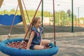 Happy little child girl laughing and swinging on a swing in the city park in summer Royalty Free Stock Photo