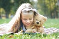 Happy little child girl looking in her mobile phone with her favorite teddy bear toy outdoors in summer park Royalty Free Stock Photo