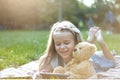 Happy little child girl playing her sellphone together with favorite teddy bear toy outdoors in summer park Royalty Free Stock Photo