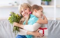 Happy little child greeting happy aged woman with flowers Royalty Free Stock Photo