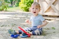 Happy little child having fun playing with sand and colorful toys in the park, beautiful summer sunny day in children playground Royalty Free Stock Photo