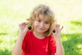 Happy little child hold cherry ner face. Kid picking and eating ripe cherries in summer park. Child holding fresh fruits Royalty Free Stock Photo