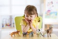 Happy little child plays animal toys at home or daycare centre