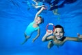 Happy little children, a boy and a girl, play and have fun under the water in the children`s pool. They swim with their Royalty Free Stock Photo