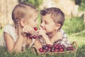 Happy little children lying near the tree with a basket of cherries at the day time. Royalty Free Stock Photo