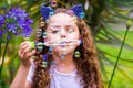 Happy little curly girl playing with soap bubbles on a summer nature, wearing a blue ears of tiger accessories over her Royalty Free Stock Photo