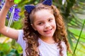 Happy little curly smiling girl playing with soap bubbles on a summer nature, wearing a blue ears of tiger accessories Royalty Free Stock Photo