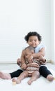 Happy Little cute African chubby kid girl hugging her newborn baby sister in arms while sitting playing together on floor at home Royalty Free Stock Photo