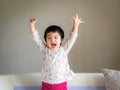 Happy little cute girl laughing and raise the hand up on the sofa. Happy, Children, Family Concept. Royalty Free Stock Photo