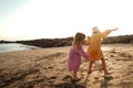 Happy little cute girls enjoying sunny day at the beach, playing and running on the sand. Family summer vacation. Sister`s love Royalty Free Stock Photo