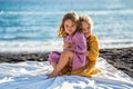 Happy little cute girls enjoying sunny day at the beach, standing on the coast and looking at the waves. Family summer vacation. Royalty Free Stock Photo