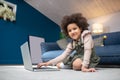 Happy little darkskinned girl with laptop sitting on floor