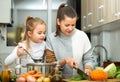 Happy little daughter and woman preparing vegetable soup Royalty Free Stock Photo