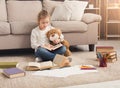 Happy little female child hugging her teddy bear and reading Royalty Free Stock Photo