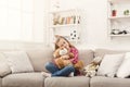 Happy little female child hugging her teddy bear on sofa at home Royalty Free Stock Photo