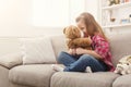 Happy little female child hugging her teddy bear on sofa at home Royalty Free Stock Photo
