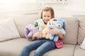 Happy little female child hugging her toy rabbits on sofa at home Royalty Free Stock Photo