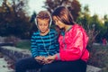 Happy little friends, boy and girl with headphones sharing music from a smart phone outdoor Royalty Free Stock Photo