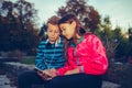 Happy little friends, boy and girl with headphones sharing music from a smart phone Royalty Free Stock Photo