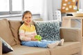 Happy little girl with apple sitting on sofa Royalty Free Stock Photo