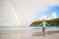 Happy little girl backgound the beautiful rainbow over the sea. Beautiful rainbow on caribbean beach Royalty Free Stock Photo