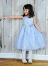 Happy little girl in beautiful blue dress pointing