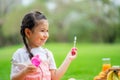 Happy little girl blowing soap bubbles playing alone in the park Royalty Free Stock Photo