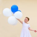 Happy little girl with blue and white balloons. Royalty Free Stock Photo