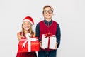 Happy little girl and boy in Santa hat, stylish brother and sister, happily holding Christmas gifts in their hands, and looking at Royalty Free Stock Photo