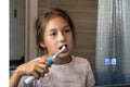 A happy little girl brushes her teeth in front of a mirror in the bathroom. Morning routine. Hygiene. Royalty Free Stock Photo