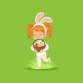 Happy little girl with bunny ears and rabbit costume holding basket with painted eggs, kid having fun on Easter egg hunt Royalty Free Stock Photo