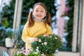 Happy little girl caring for balcony flowers, pruning with pruning shears Royalty Free Stock Photo