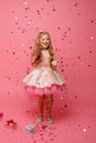 Happy Little girl catches confetti on pink background, holiday concept