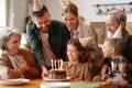 Happy little girl celebrating birthday with family at home, looking at cake with lit candles Royalty Free Stock Photo