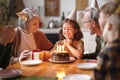 Happy little girl celebrating birthday with family at home, looking at cake with lit candles Royalty Free Stock Photo