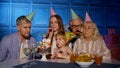 Girl celebrating birthday party with parents, senior grandparents family blowing out candles on cake Royalty Free Stock Photo