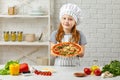 Happy little girl in chef hat and an apron cooking pizza Royalty Free Stock Photo