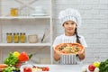 Happy little girl in chef hat and an apron cooking pizza Royalty Free Stock Photo