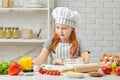 Happy little girl in chef hat and an apron cooking pizza Royalty Free Stock Photo