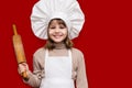 Happy little girl in chef uniform holds rolling pin isolated on light background. Kid chef Royalty Free Stock Photo