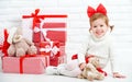 Happy little girl child with Christmas gifts at wall