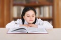 Happy little girl child reads book in library Royalty Free Stock Photo