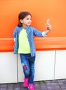 Happy little girl child taking picture self portrait on smartphone in city over colorful Royalty Free Stock Photo
