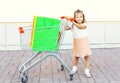 Happy little girl child and trolley cart with colorful shopping bags in city Royalty Free Stock Photo