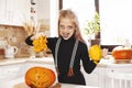 Happy little girl in costume and holiday makeup with scary look at halloween party with big pumpkin Royalty Free Stock Photo