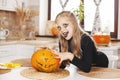 Happy little girl in costume and holiday makeup with scary look at halloween party with big pumpkin Royalty Free Stock Photo