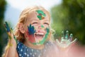 Happy, little girl covered in paint and outdoors with a lens flare. Happiness or creative, playing or art fun and